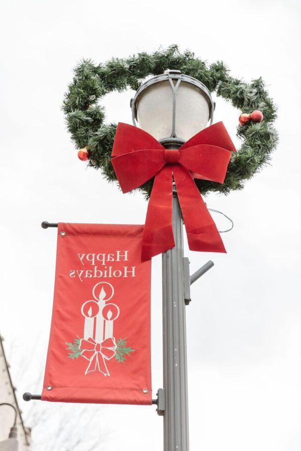 A wreath and Happy Holidays banner on a street lamp